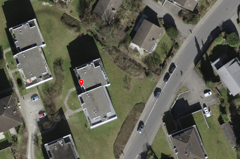 Aerial view of two semi-detached houses with parking spaces in front and a road next to them.