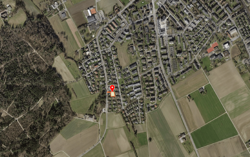 Aerial view of a town with many buildings, surrounded by fields and trees.