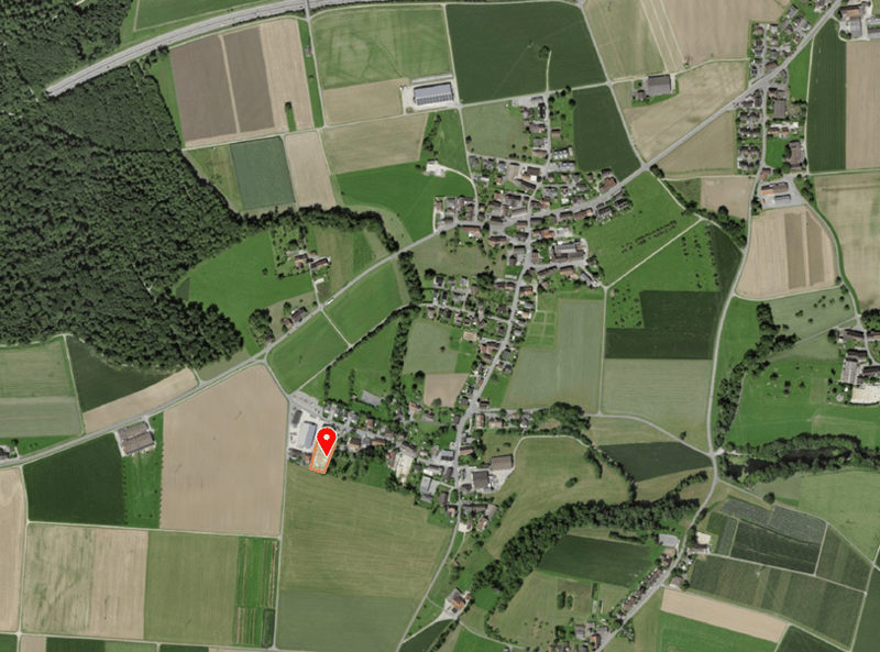 Aerial view of a rural area with several fields, a small town, and a highway.