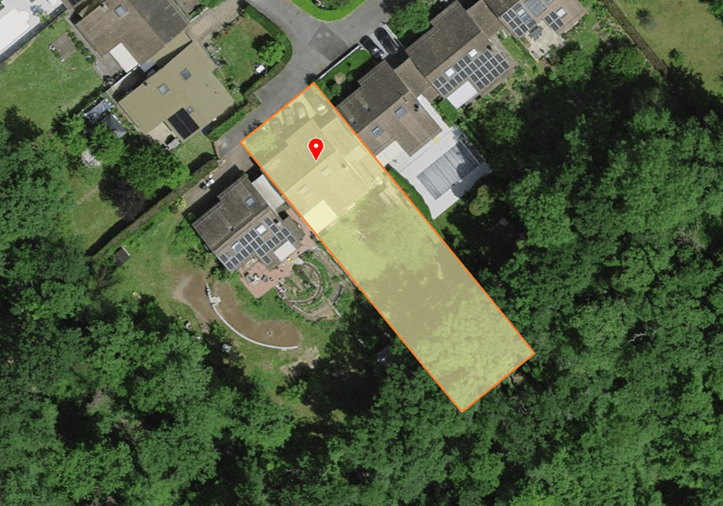 Plot of land with a house and garden, surrounded by trees and greenery