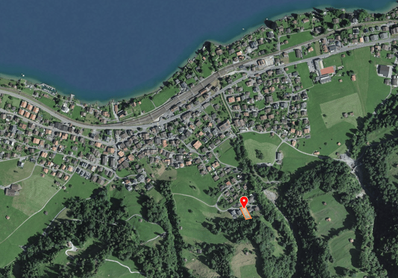 Aerial view of a village with many houses, green fields, and a body of water.
