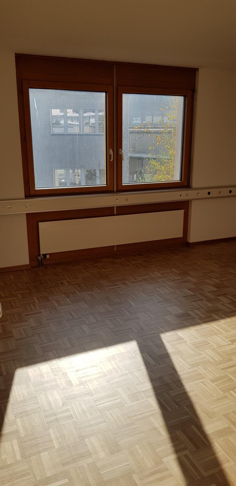 Empty room, large windows, parquet flooring, central heating radiator
