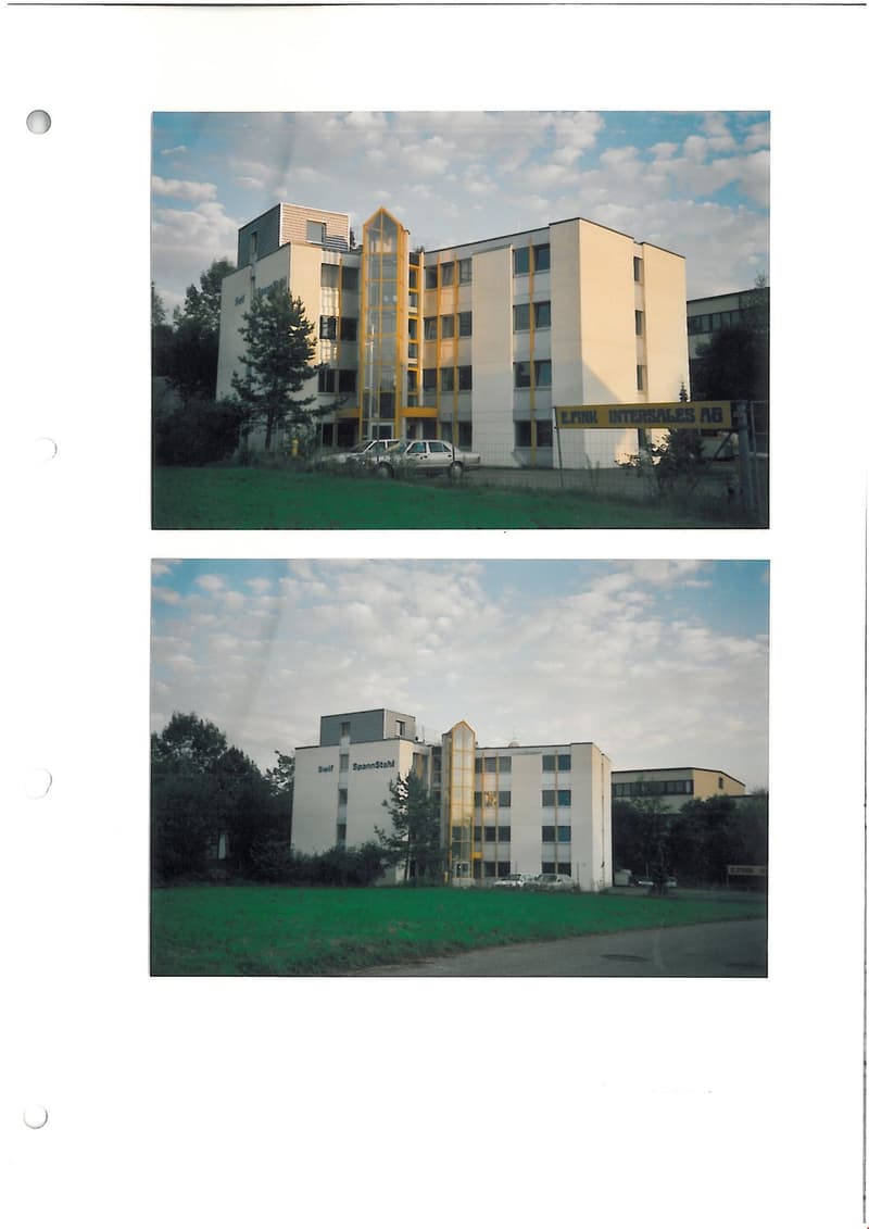 Multistory building, large windows, yellow accent, large field, multiple cars in front