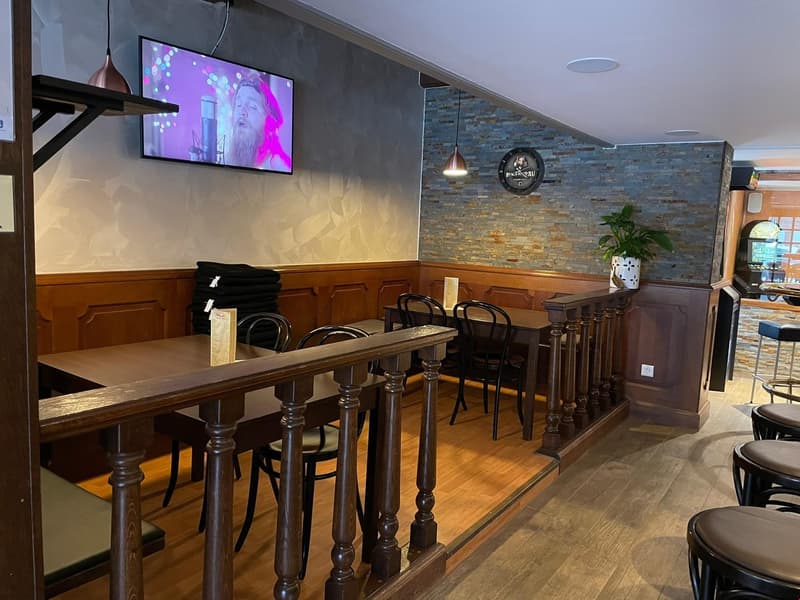 wooden tables, chairs, metal railing, TV, potted plant, brick wall, stools