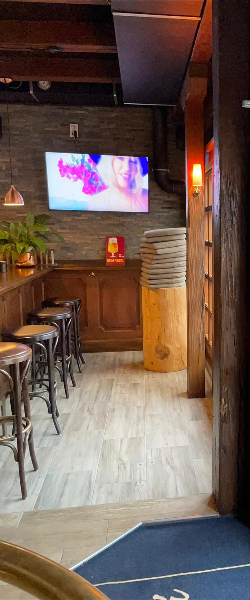 Bar counter with stools, flatscreen television mounted on wall, stack of bar mats