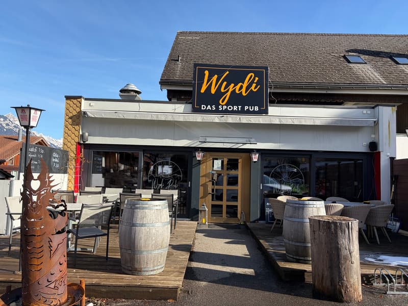 Outdoor dining area, tables and chairs, barrels, lamp, metal pole with sign