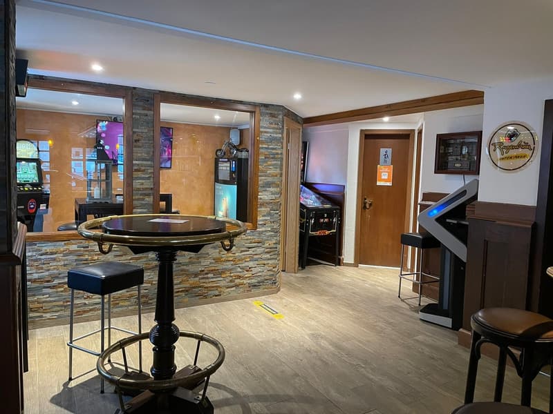 wooden table, stools, gaming machines, brick wall, digital screen, door