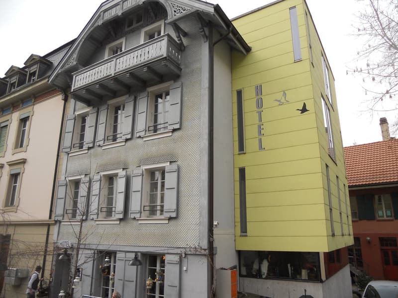 Multi-story hotel building, metal facade, balcony on the second floor, glass windows, glass doors