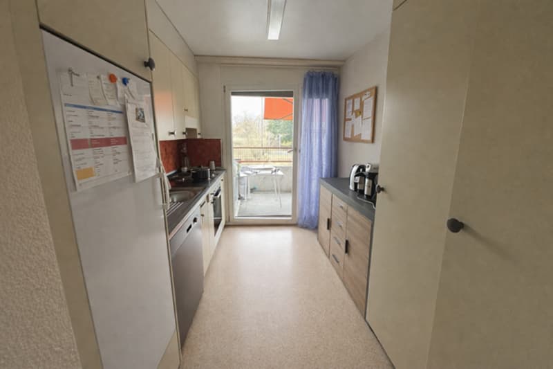 White refrigerator, gas stove, sink, kitchen cabinets, blue curtain, balcony with awning