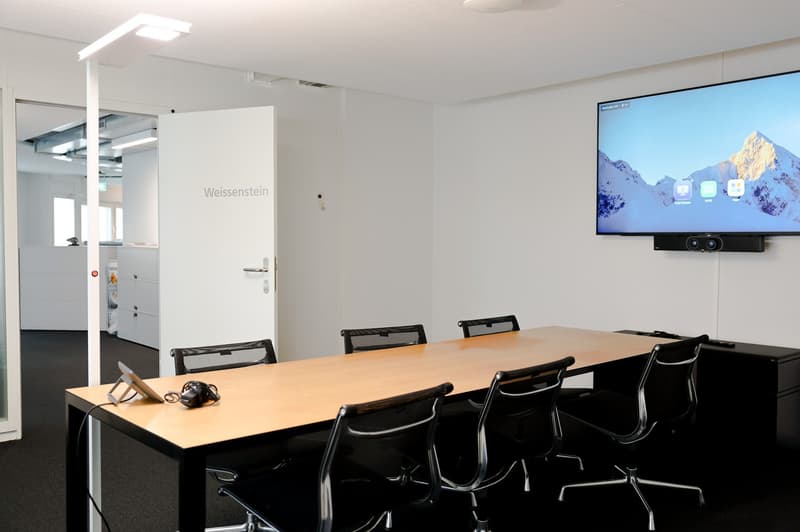 conference room with a long table, chairs, monitor, and a door