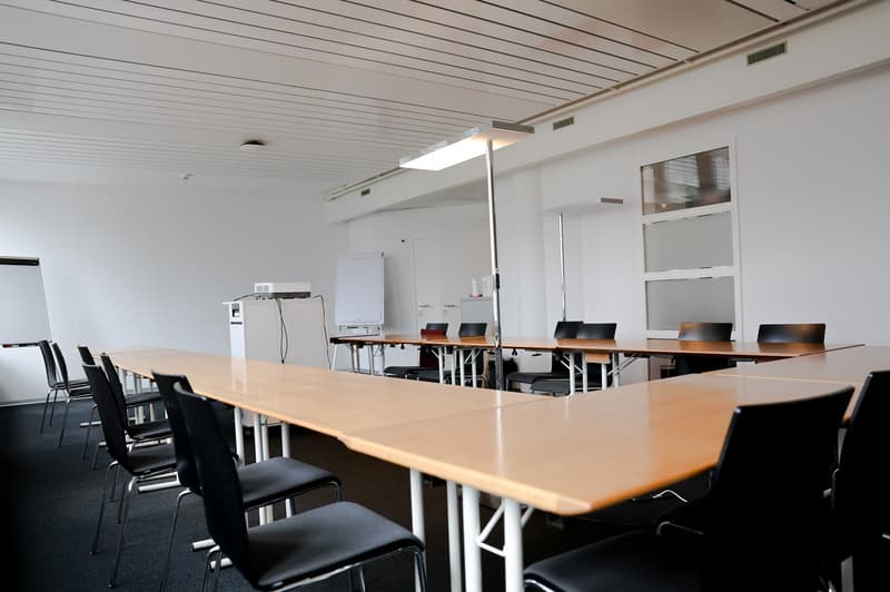 empty conference room with long tables, chairs, whiteboards, lamps