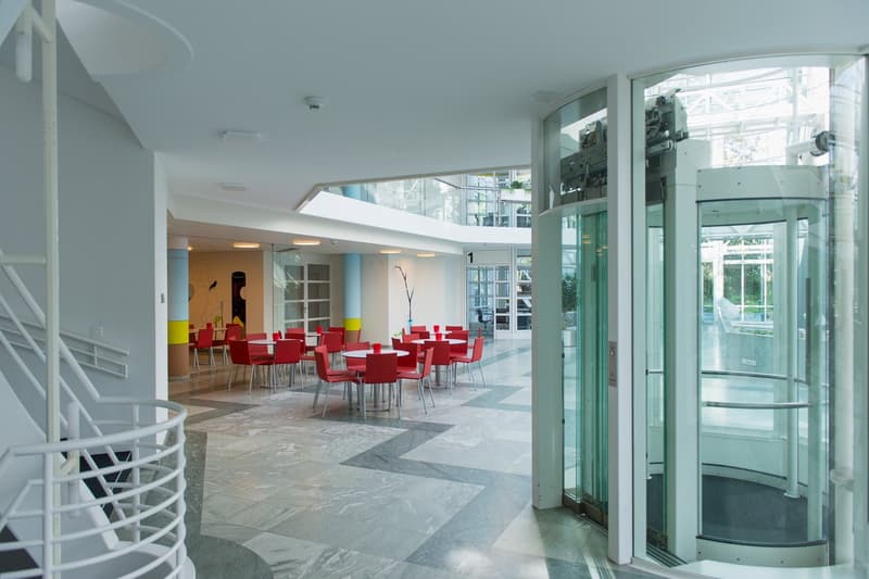 modern building, spiral staircase, round tables and chairs, glass elevator, glass walls