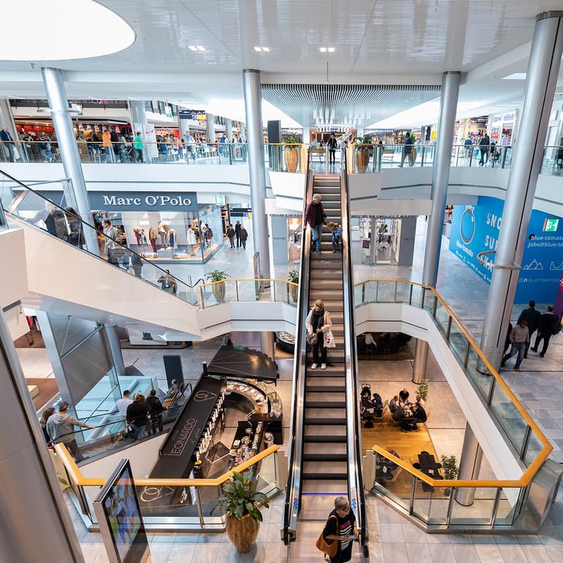 Open shopping mall, multiple levels, escalators, food court, several shops and cafes.
