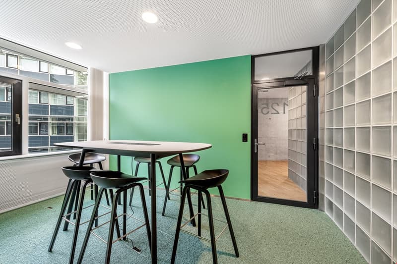 modern room, round white table, black chairs, green wall, glass partition, storage boxes