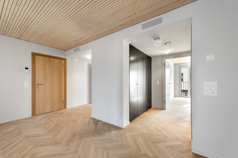 Empty room with wooden floor, white walls, wooden door, built-in wardrobe, and ceiling lights