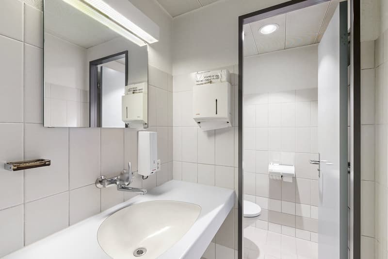 Tiled bathroom with a sink, mirror, and two wall-mounted appliances (likely a washing machine and a dishwasher)