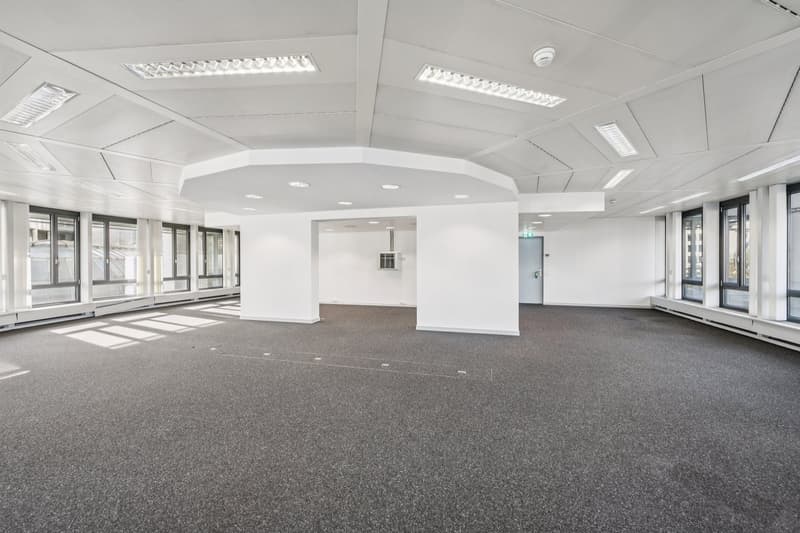 empty office space with white ceiling, white walls, large windows, white floor