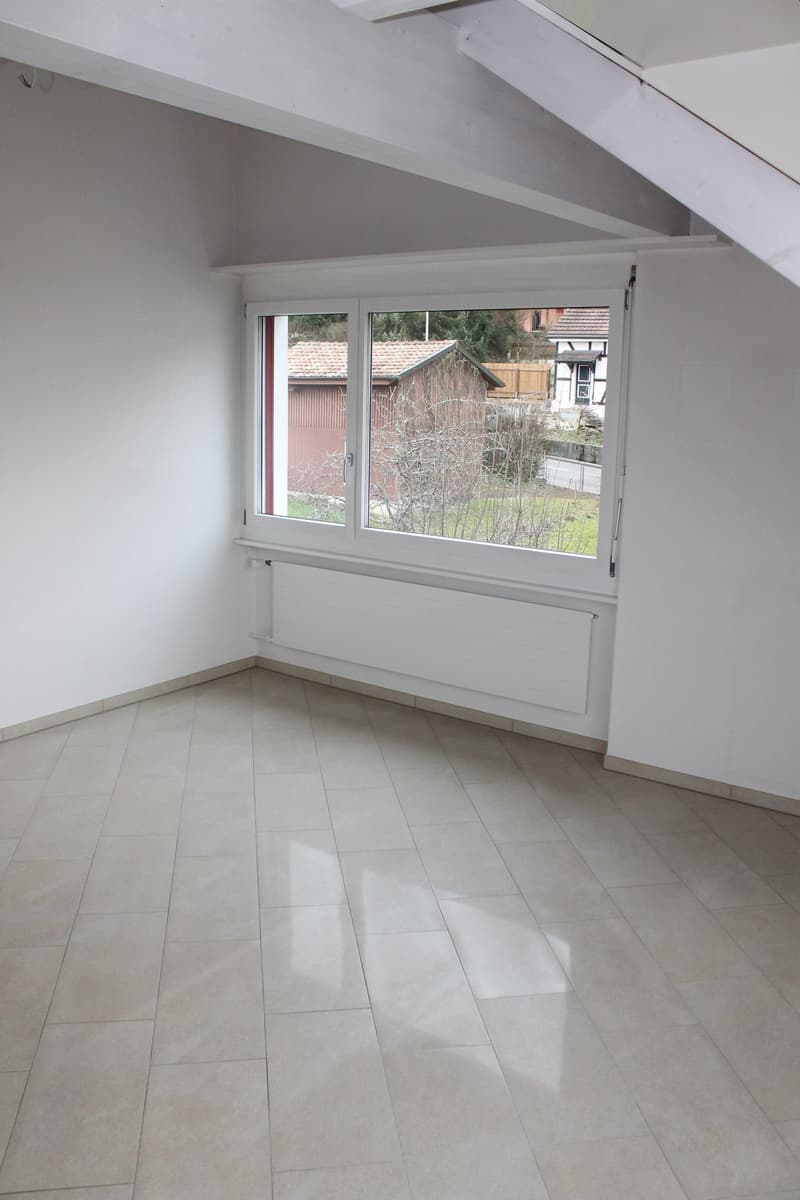 Empty room with white walls, beige tiles, a double window, and a radiator below it.
