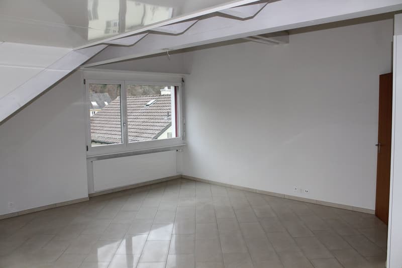 Empty room with white walls, white ceiling, white radiator, wooden door, tiled floor.