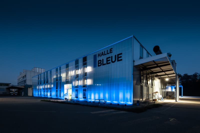 modern building, blue lighting, entrance, bicycle parking, benches, potted plants, reflective windows