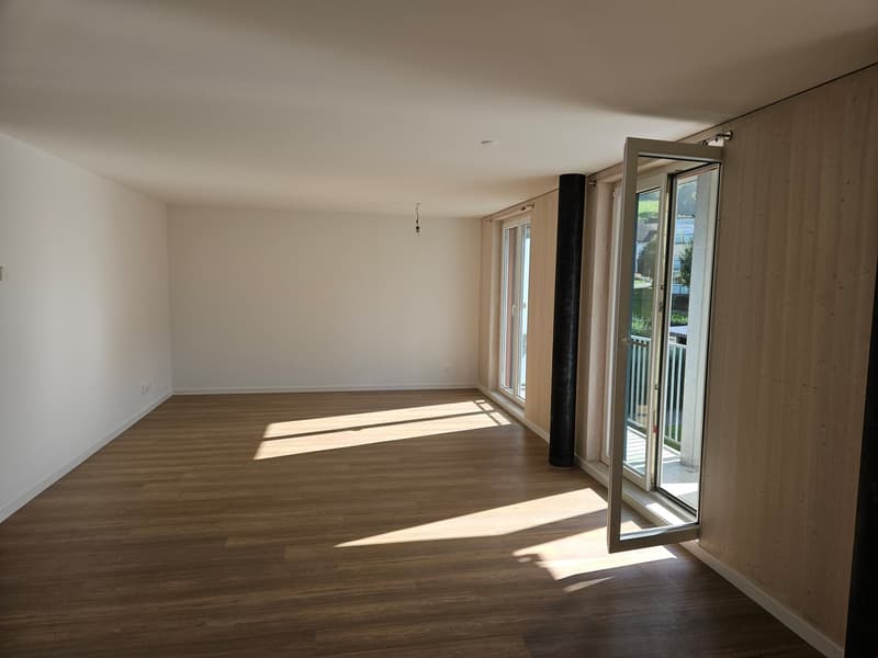 Wohnzimmer mit bodentiefen Fenstern und direktem Zugang zum Balkon