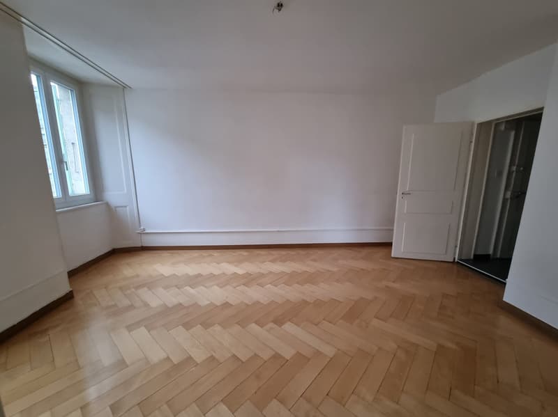 Empty room, wooden floor, large windows, white walls, white doors