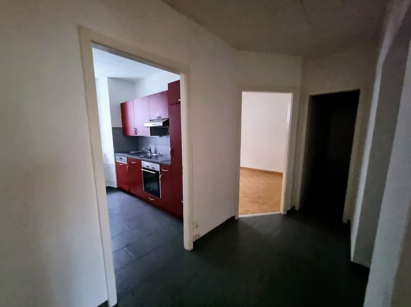 Red cabinets, black tiled floor, sink, dishwasher, oven