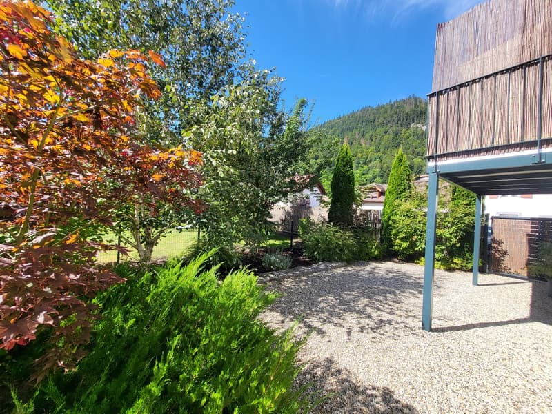 gravel driveway, trees, shrubs, balcony, mountains in the background