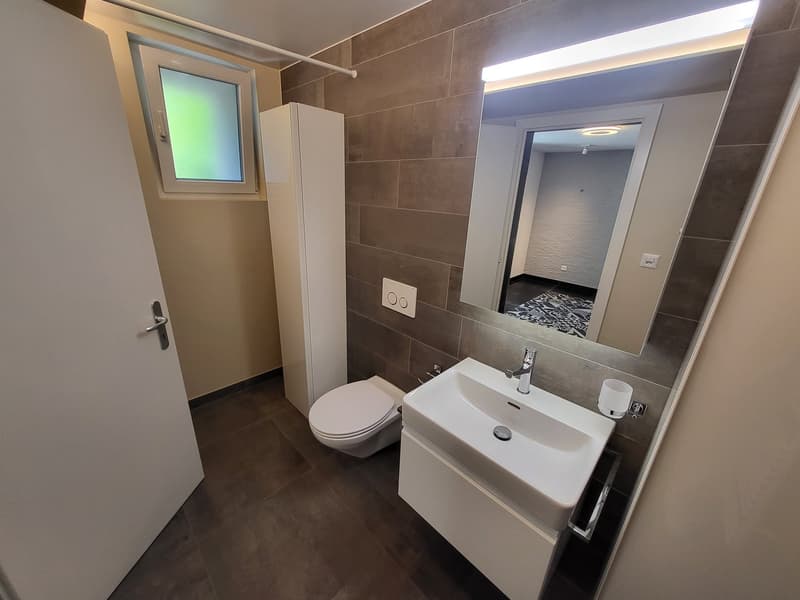 modern bathroom with white sink, mirror, toilet, and tiled floor