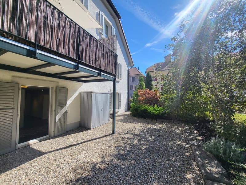 white house, balcony, gravel driveway, storage shed, plants, trees