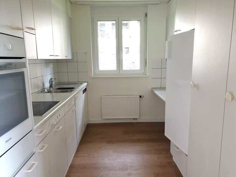 modern kitchen with white cabinets, wooden floor, white tiles, double sink, oven, window