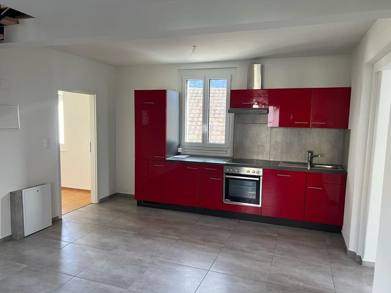 Modern kitchen with red cabinets, stainless steel appliances, tiled floor, large window with outdoor view