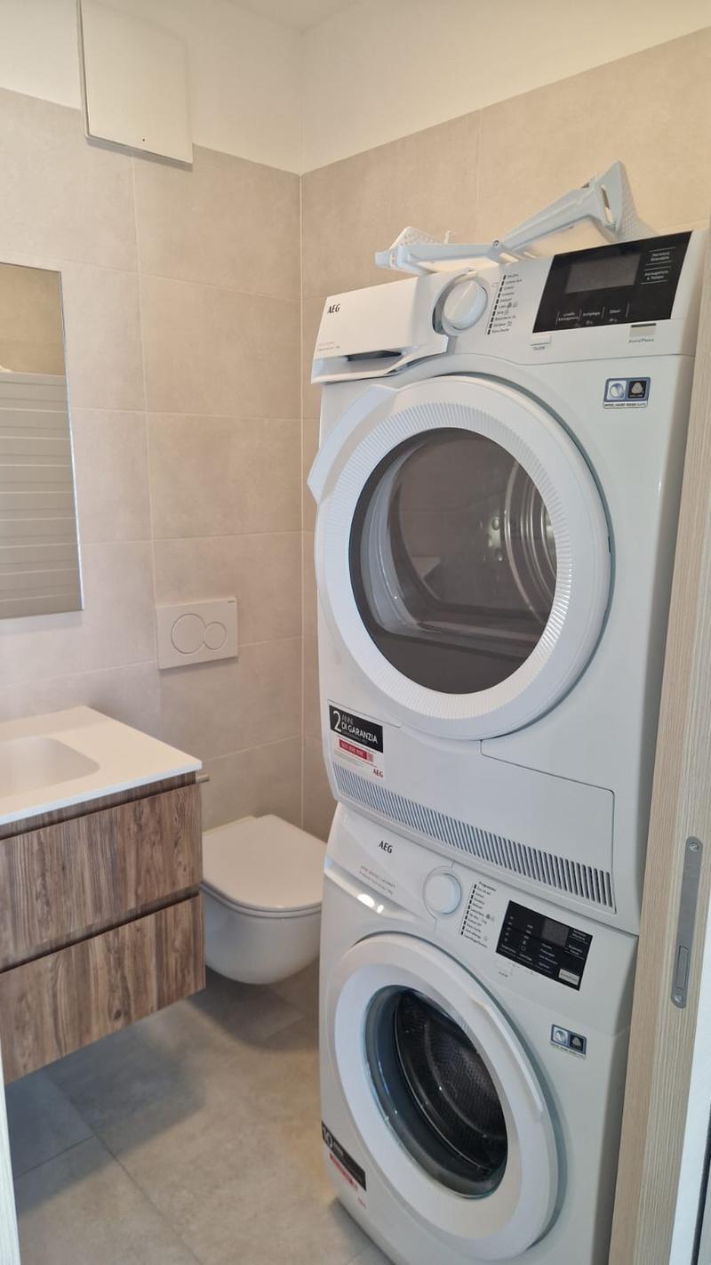 stacked washing machine and dryer, toilet, sink, mirror
