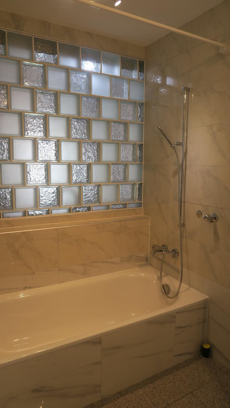 Bathroom with bathtub, shower, and glass block wall