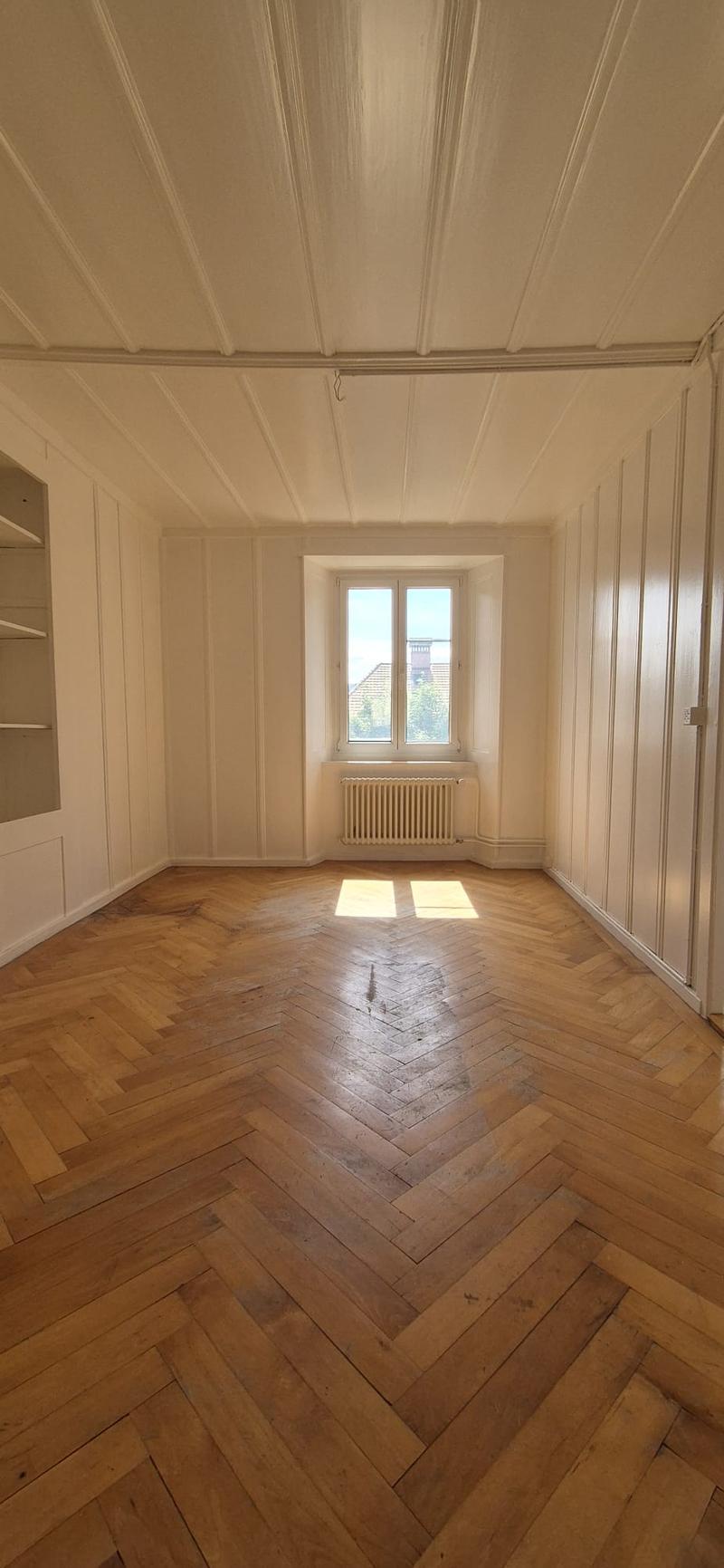 empty room, wooden parquet floor, white walls, white ceiling, window, radiator