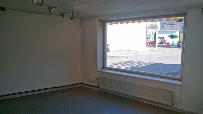 empty room, large window, white walls, white floor, white radiator, power outlets