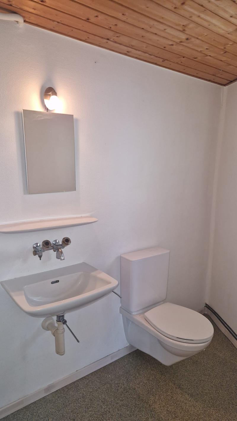 Bathroom with white sink, white toilet, mirror, and wooden ceiling