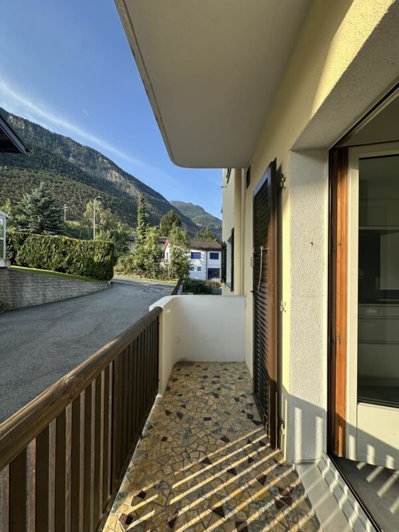 Balcony with wooden railing, tiled floor, glass door, view of mountains