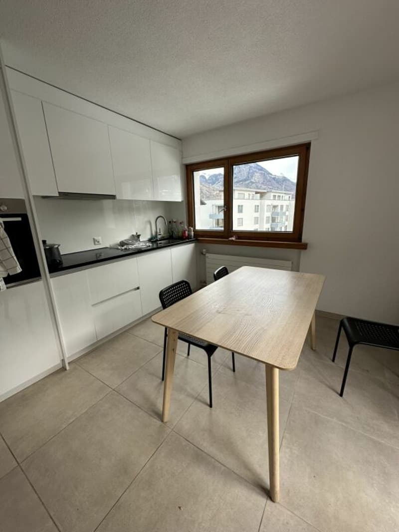 modern kitchen with white cabinets, wooden table, black chairs, large window, tiled floor