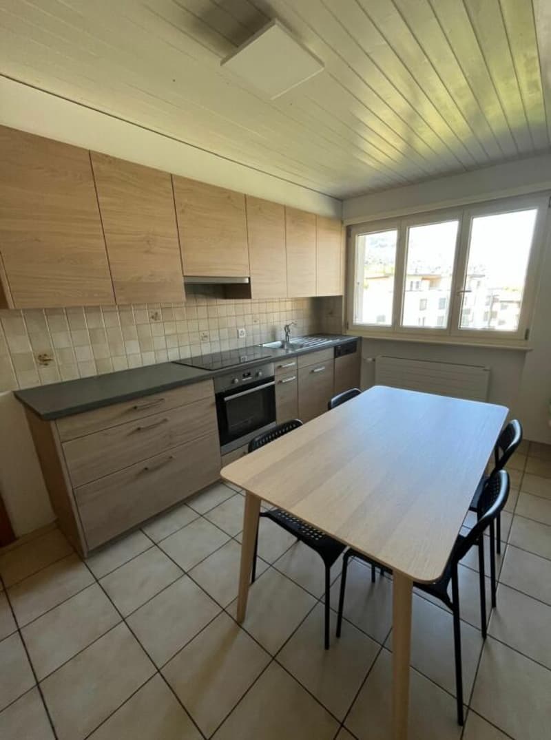 modern kitchen with wooden cabinets, tiled floor, large windows, table and chairs, oven, sink, dishwasher