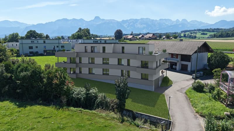 3-story building, balconies, surrounded by greenery, mountain view