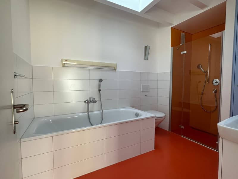 white tiles, bathtub, toilet, glass shower, white sink, red floor