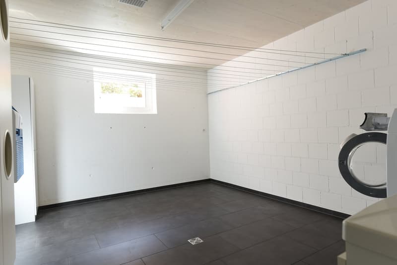 Empty room with white walls, black tiled floor, washing machine, and dishwasher.