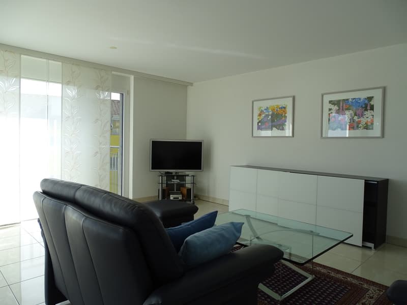black sofa, glass coffee table, carpet, entertainment center, tv, pictures