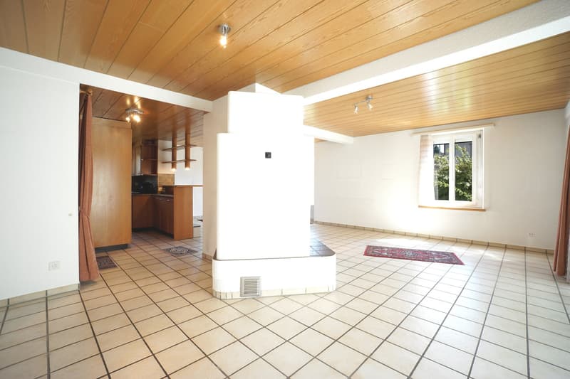 Empty room with white tiles on the floor, wooden ceiling, a column in the middle, a rug, and a window