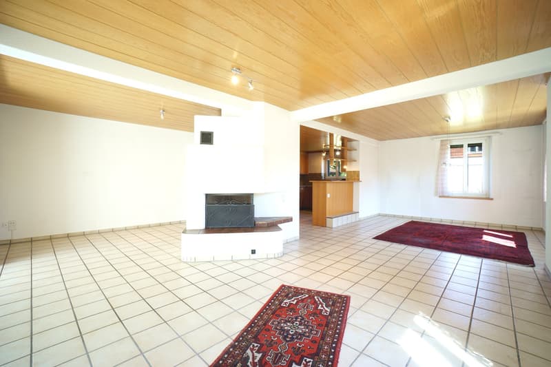 white tiles, wooden ceiling, white walls, fireplace, 2 red rugs, open area, windows
