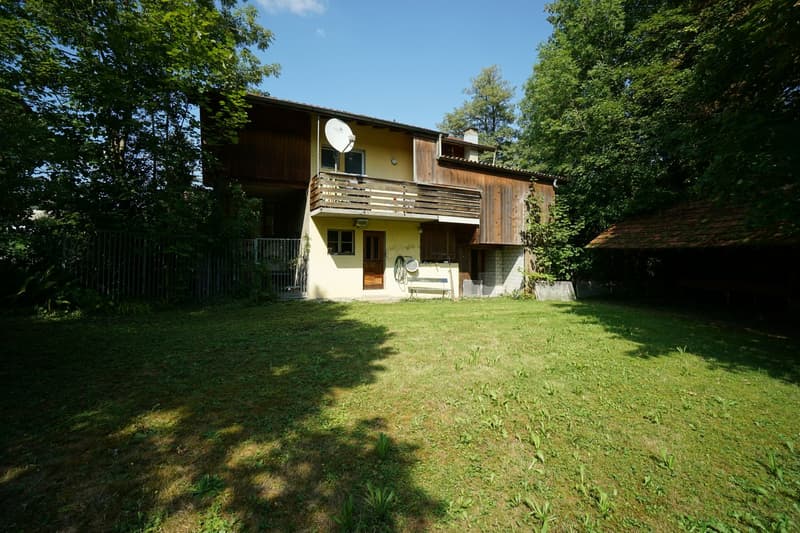 House with wooden exterior, satellite dish, balcony, surrounded by lush greenery