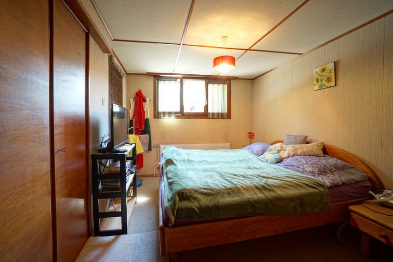 double bed with green blanket, shelves, TV, window with balcony access
