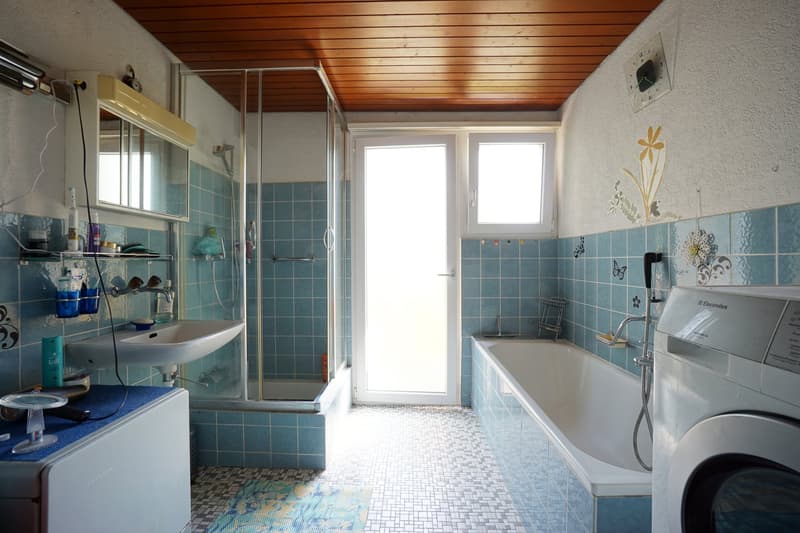 bathroom with bathtub, sink, toilet, shower enclosure, blue tiles, wooden ceiling, washing machine