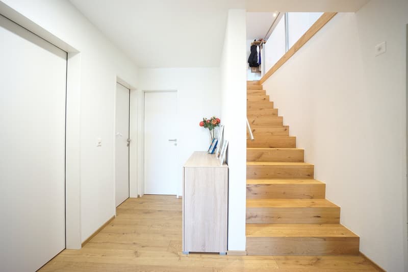 wooden stairs, white walls, wooden floor, white doors, flower vase, picture frames